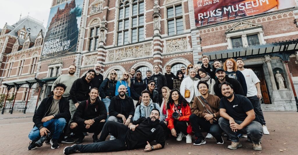 A large group poses in front of the iconic Rijksmuseum in Amsterdam, capturing a memorable moment for tourism and culture.