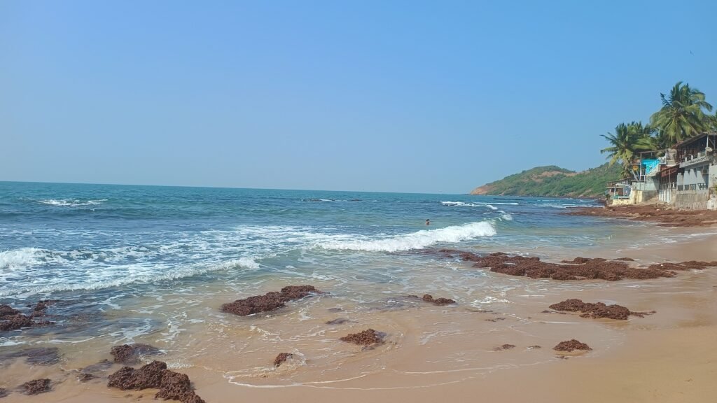 Beautiful Anjuna Beach in Goa with waves and clear skies.